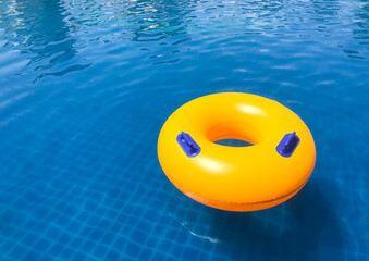 Yellow Ring floating in a refreshing blue swimming pool with wave reflecting in the summer time.