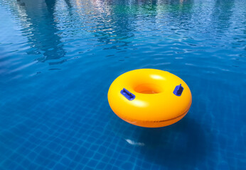 Yellow Ring floating in a refreshing blue swimming pool with wave reflecting in the summer time.