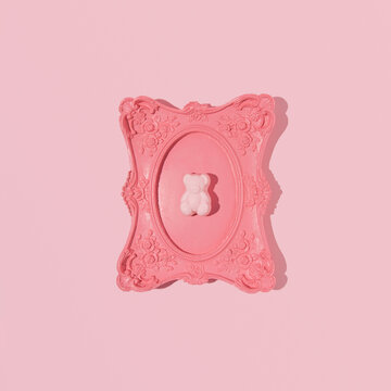 Gummy bear framed in a vintage romantic wall frame, creative aesthetic layout, candy pink background. Retro girly style. 