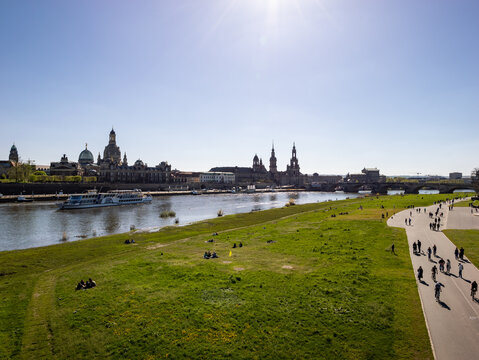 Crowded Elbe cycle path on a sunny spring day. A lot of people enjoying the warm weather outdoors. The old town cityscape is in the background. Beautiful architecture in the city in Saxony.