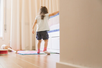 Small Caucasian girl playing in her bedroom, developing fine motor skills by getting on and off the...