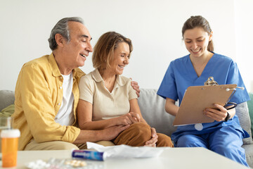 Visit to patient. Nurse talking with senior couple, holding clipboard in conversation with aged man and woman - Powered by Adobe