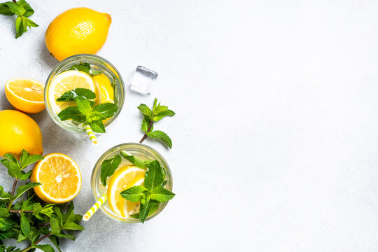 Lemonade in glass with fresh lemons and mint. Cold summer drink top view with copy space.