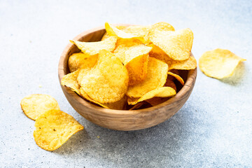 Potato chips in wooden bowl on white table. Top view with copy space.