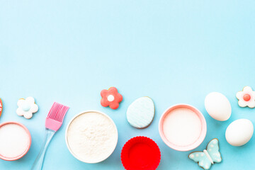 Easter baking background on blue. Flour, edds, sugar and gingerbread cookies. Top view with copy space.