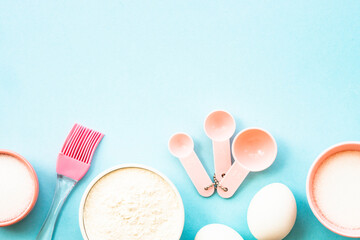 Ingredients for cooking baking on blue. Flour, sugar, eggs and utensils. Top view with space for text.