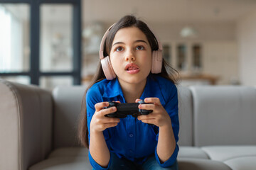 Preteen Girl With Headphones Playing Video Game Online At Home © Prostock-studio