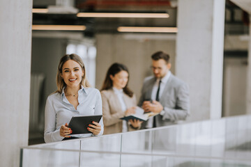 Young business woman with digital tablet in the office hallway