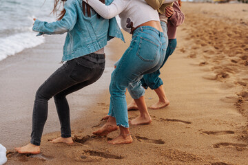 Four young woman running from waves on beach.