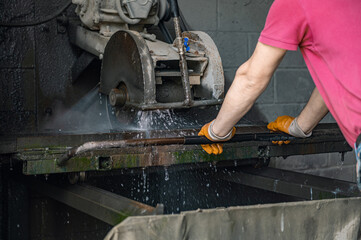 A worker cuts granite. The cutter cuts granite. Stone processing machine.