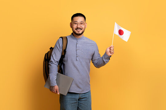 Asian Young IT Guy With Laptop And Flag Of Japan In Hands