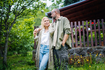 Caucasian happy relaxed middle age couple enjoying summer in country house standing on hugging in...