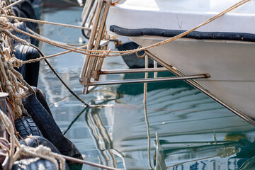 Reflection in the sea surface of white yachts parked in the port on the shore. Fragment of a ship...