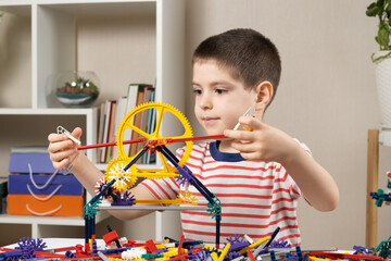 A little boy plays with a constructor, creating figures from gears and sticks. Development of logic...