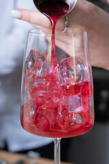 Bartender preparing alcoholic cocktails with ice in glasses on the bar table