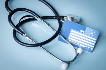 European health insurance card next to a medical stethoscope. Concept, EU document confirming the...