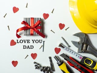 Construction tools, hard hat and wrapped gift box with a bow on white background with Love you dad. Construction greeting card for Dad on Fathers day. For advertising or web design. Flat lay