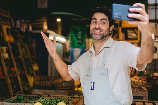 middle-aged latin man greengrocer making a video with his cell phone to promote his organic store on social networks. copy space