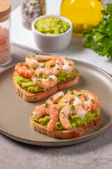 Appetizer toasted bruschetta with mashed avocado and shrimps on background. Healthy food concept with prawns.