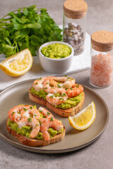 Appetizer toasted bruschetta with mashed avocado and shrimps on background. Healthy food concept with prawns.