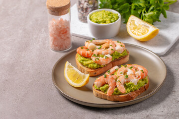 Appetizer toasted bruschetta with mashed avocado and shrimps on background. Healthy food concept with prawns.