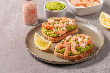 Appetizer toasted bruschetta with mashed avocado and shrimps on background. Healthy food concept with prawns.