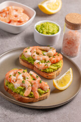 Appetizer toasted bruschetta with mashed avocado and shrimps on background. Healthy food concept with prawns.