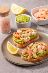 Appetizer toasted bruschetta with mashed avocado and shrimps on background. Healthy food concept with prawns.
