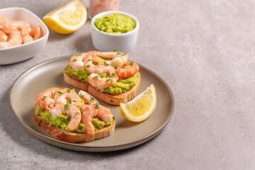 Appetizer toasted bruschetta with mashed avocado and shrimps on background. Healthy food concept with prawns.