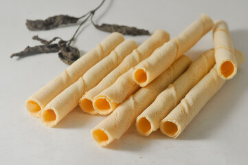 Some sticks of egg roll biscuits and a branch with dry leaves isolated on a white background