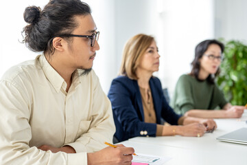 Young Japanese engineer and software programmer sitting at meeting table, cooperation concept and...
