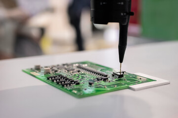 Automatic manipulator with dispenser needle working with SMT computer circuit board - close up....