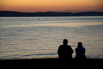 friends sitting on the waterfront at sunset