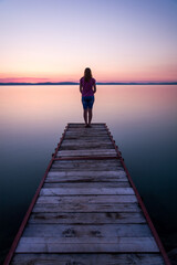 woman standing on pier at sunset