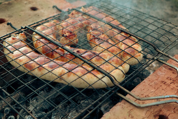 BBQ with fiery sausages on the grill. Grilled pork sausage on a cast iron grill