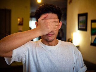 Young man covering eyes with his hand