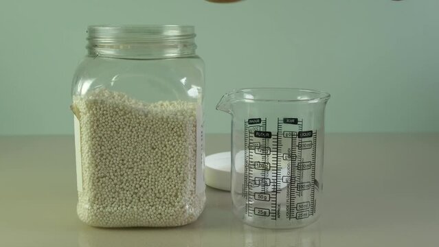 Tapioca pearls or white sago balls are poured with spoon into measuring cup. Ingredient for Boba drink, Milk bubble tea or Tapioca pudding.