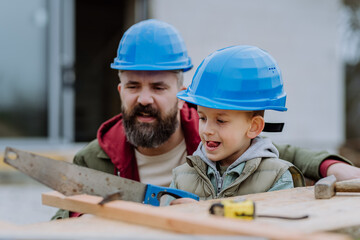 Father and his little son working in front of their unfinished house.