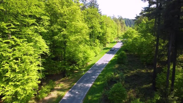 Blue Porsche Boxster Cabrio driving in the German Forest of the Mosel region close to Nurburgring Nordschleife. Cars driving on curvy roads through green woods in the sunny summer day in the hills 
