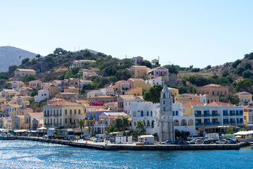 Clock Tower and houses of island Symi or Simi, Greek mountainous island and municipality, part of Dodecanese island chain. Harbor town of Symi and adjacent upper town Ano Symi