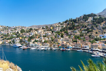 Fototapeta na wymiar Houses of island Symi or Simi, Greek mountainous island and municipality, part of Dodecanese island chain. Harbor town of Symi and adjacent upper town Ano Symi