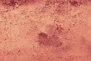 A cement wall with peeling reddish paint