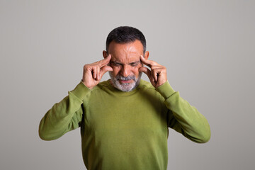 Despaired sad caucasian aged man in casual presses hands to temples, suffer from headache