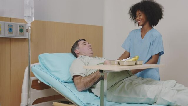 Friendly nurse talking to bedridden patient in hospital
