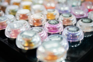 Transparent jars with mineral eyeshadow in row on counter for sale in makeup store, exhibition. Glamour, fashion, make up, beauty and skincare concept
