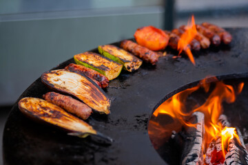Process of cooking meat sausages, zucchini, eggplant, tomato on grill, brazier at outdoor summer...