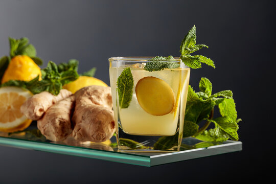 Ginger ale beer cocktail with lemon and mint in a frozen glass on a black background.
