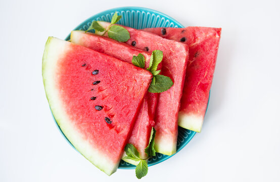 Fresh ripe slices of watermelon along with mint leaves lie on a plate on the table. Tasty and healthy, summer food.