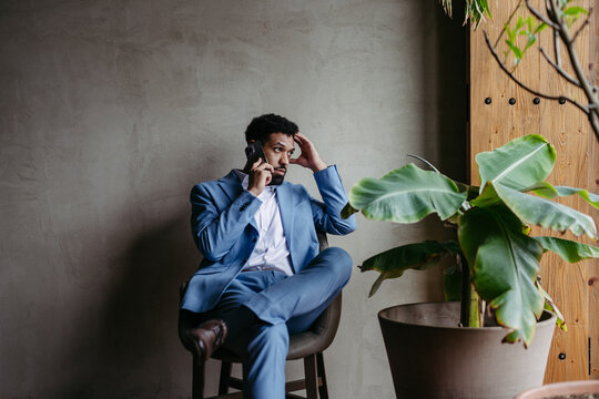 Portrait of young businessman sitting near window in green office full of plants.