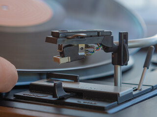 Obraz na płótnie Canvas Detail of a male hand placing a black vinyl record on a vintage turntable